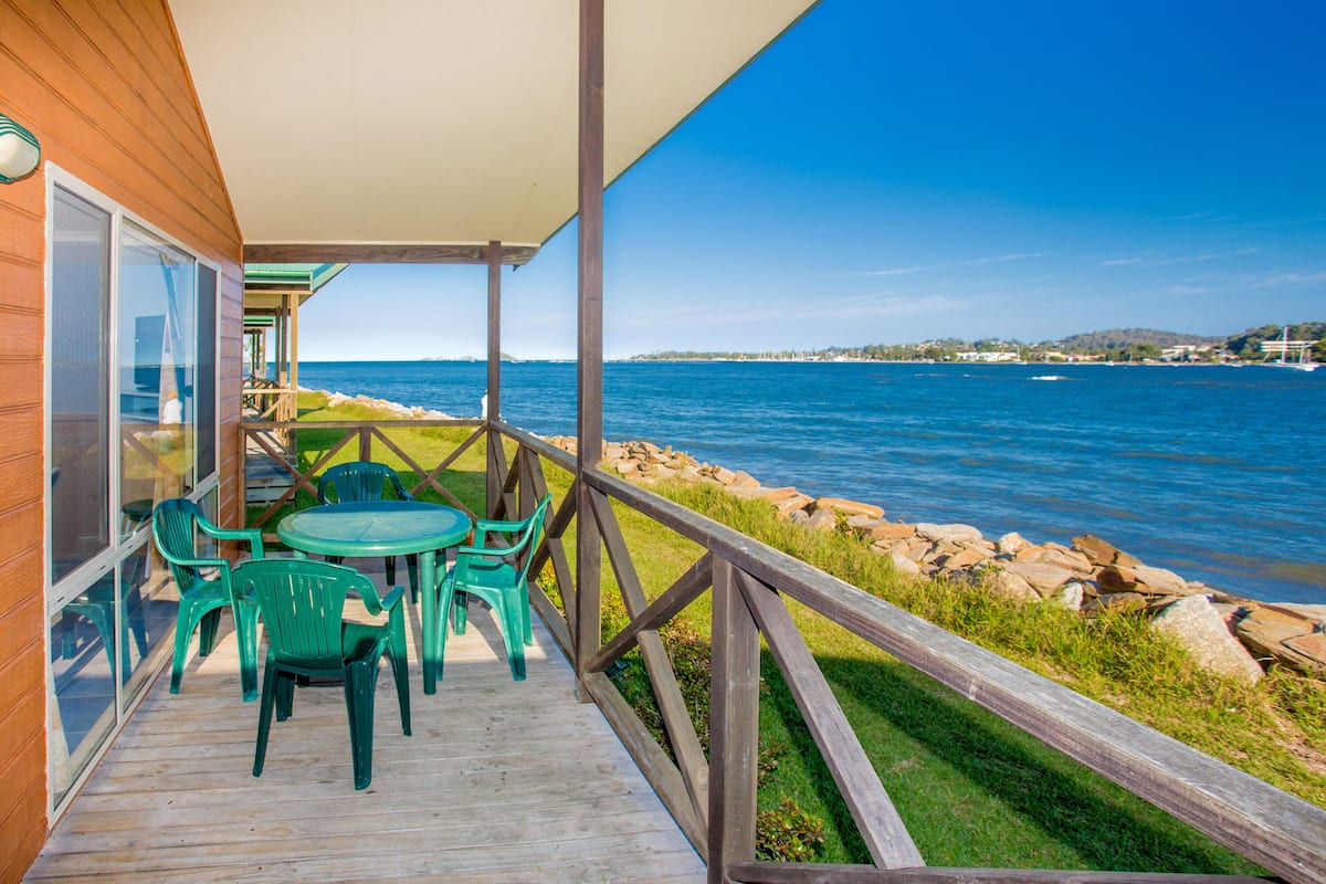A wooden deck with a table and chairs overlooking a body of water.