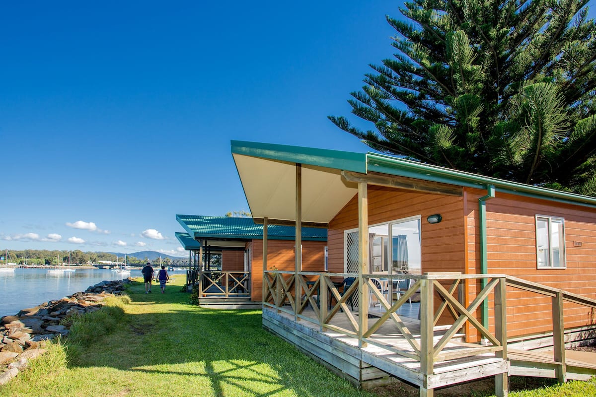 A wooden cabin with a covered porch and a view of the lake.