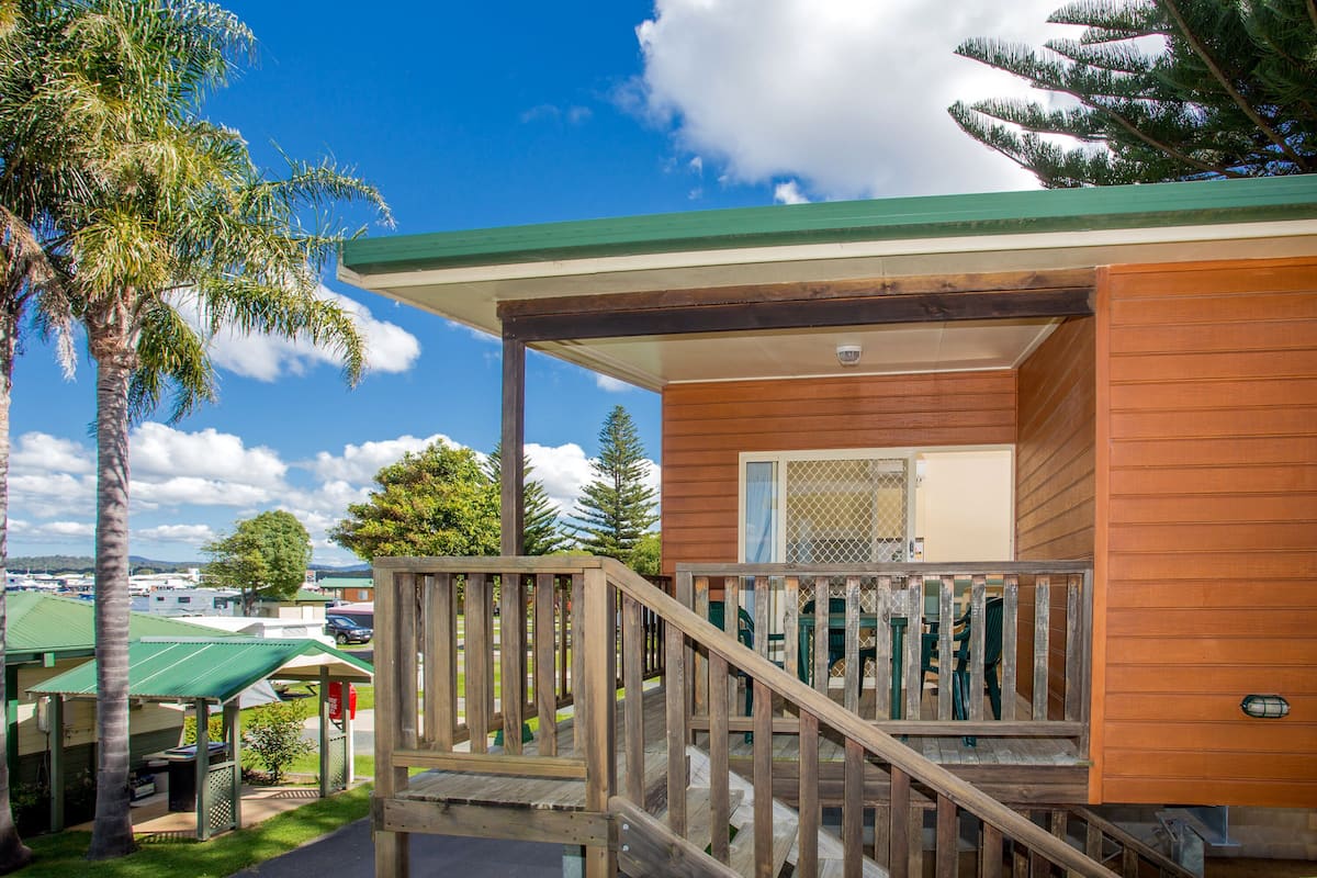 A wooden cabin with a porch and a staircase leading to a deck.