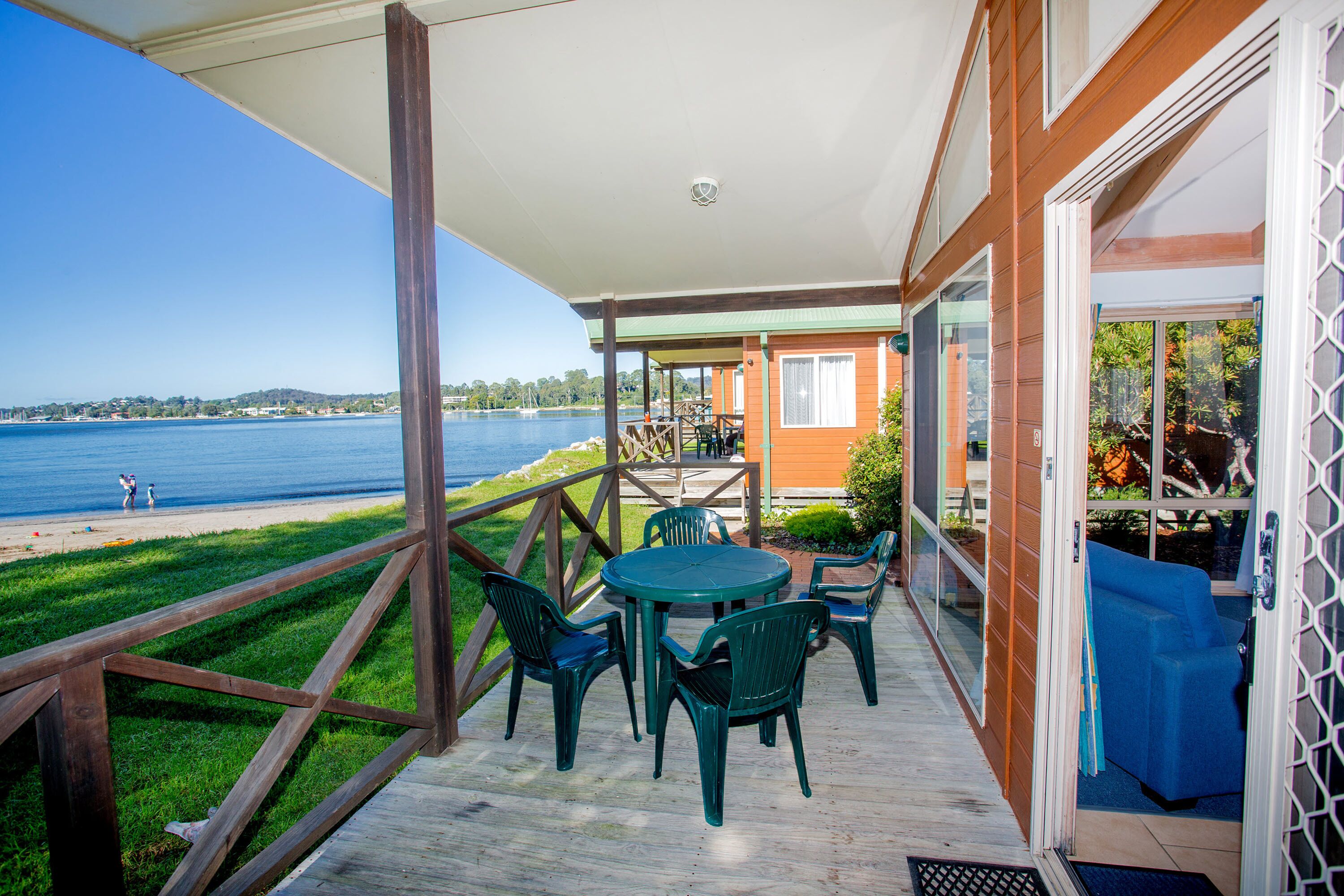 A covered outdoor area with a table and chairs, overlooking a beach and water.