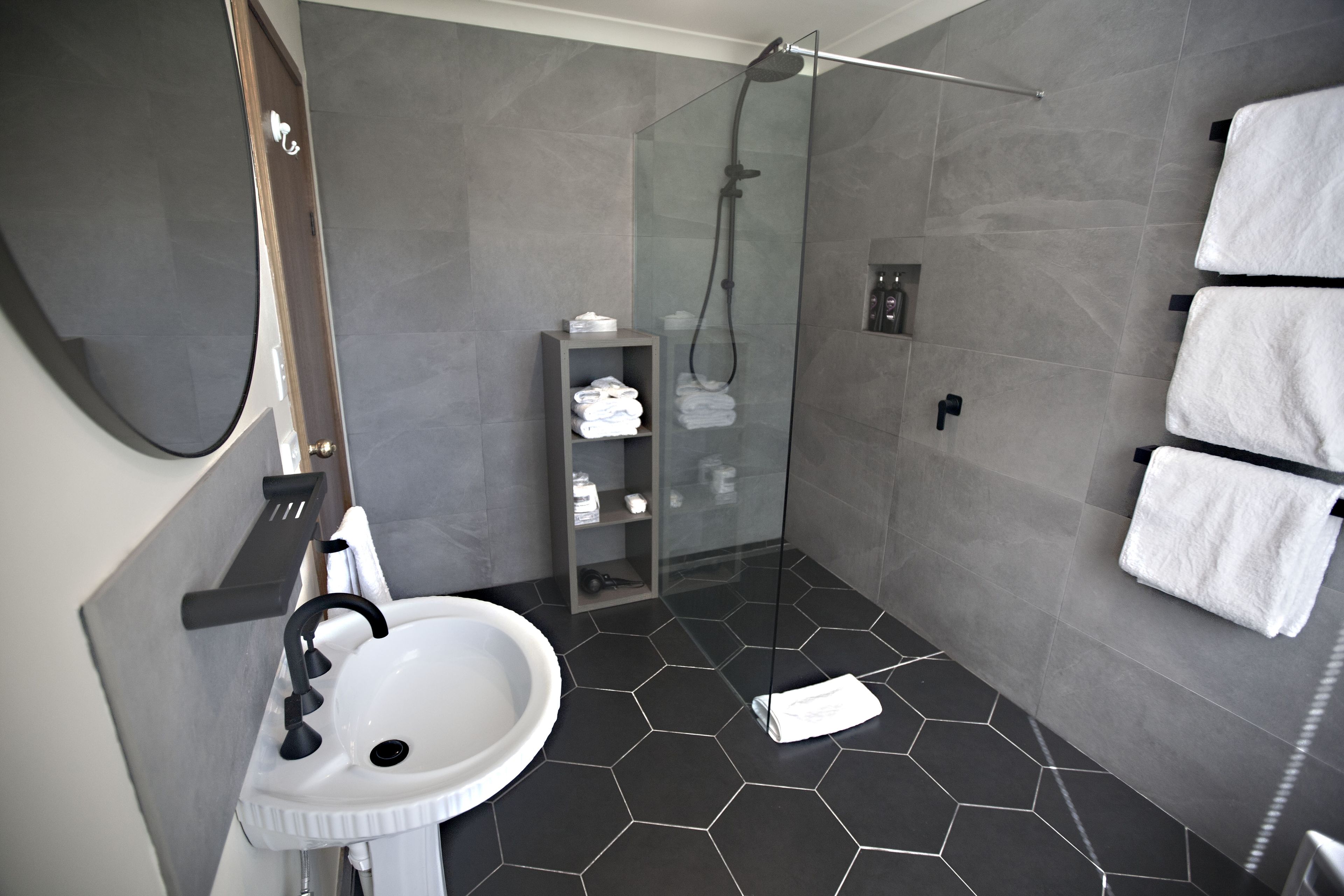 A modern bathroom with a glass-enclosed shower, a white sink, and neatly arranged towels.