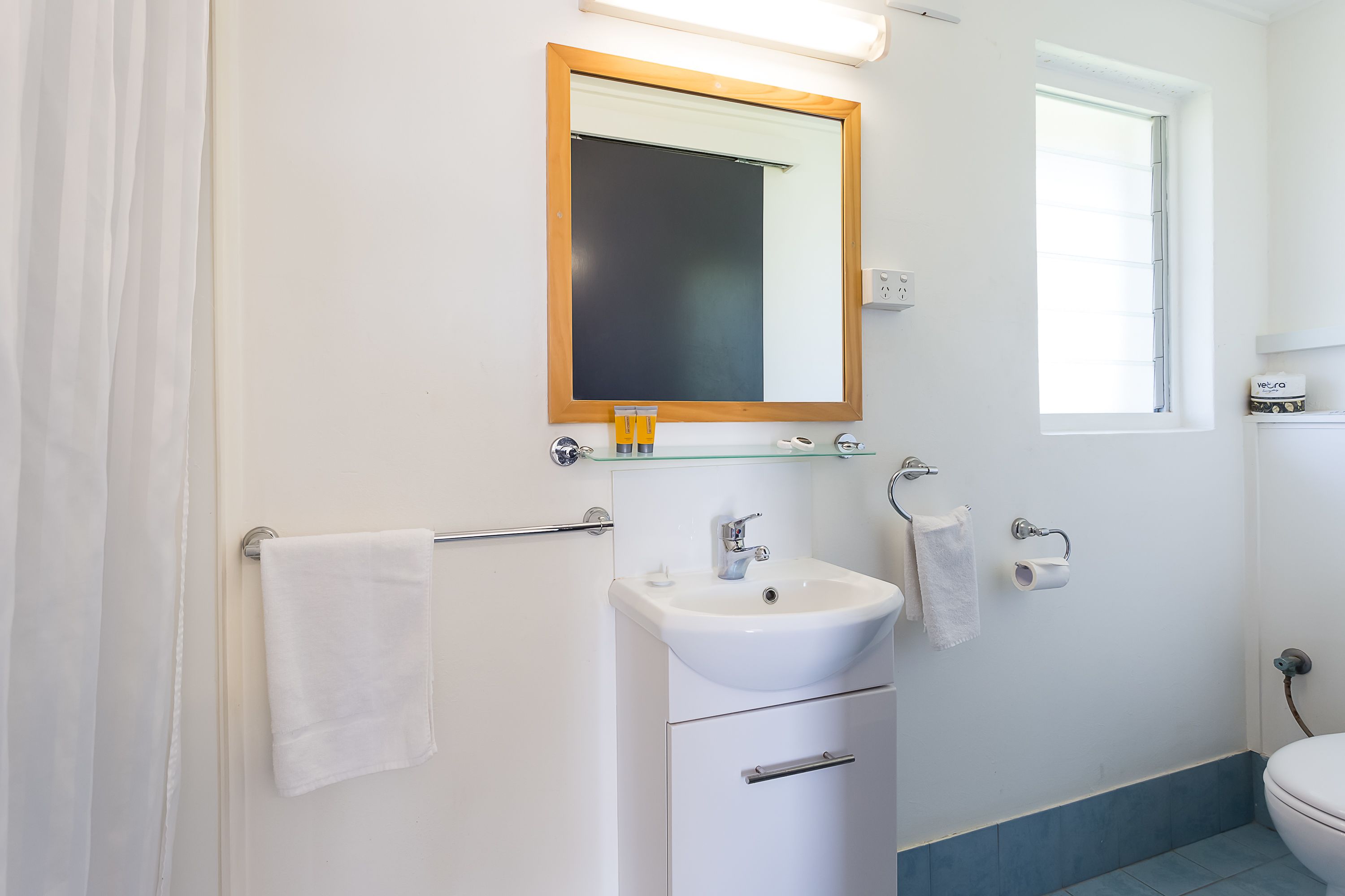 A bathroom with a white sink, mirror, and towel rack.