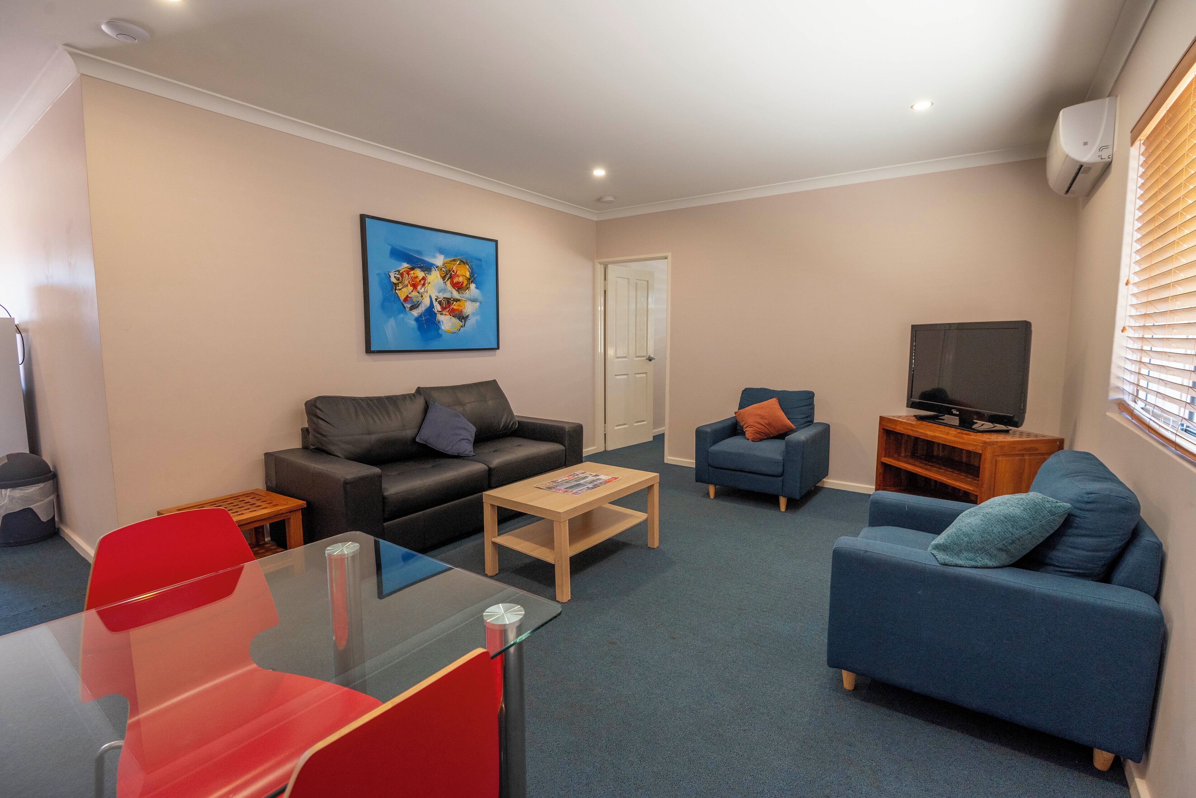 A living room with two sofas, a coffee table, a TV stand, and a painting on the wall.