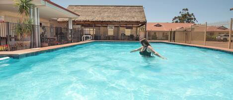 Una piscina al aire libre, sillones reclinables de piscina