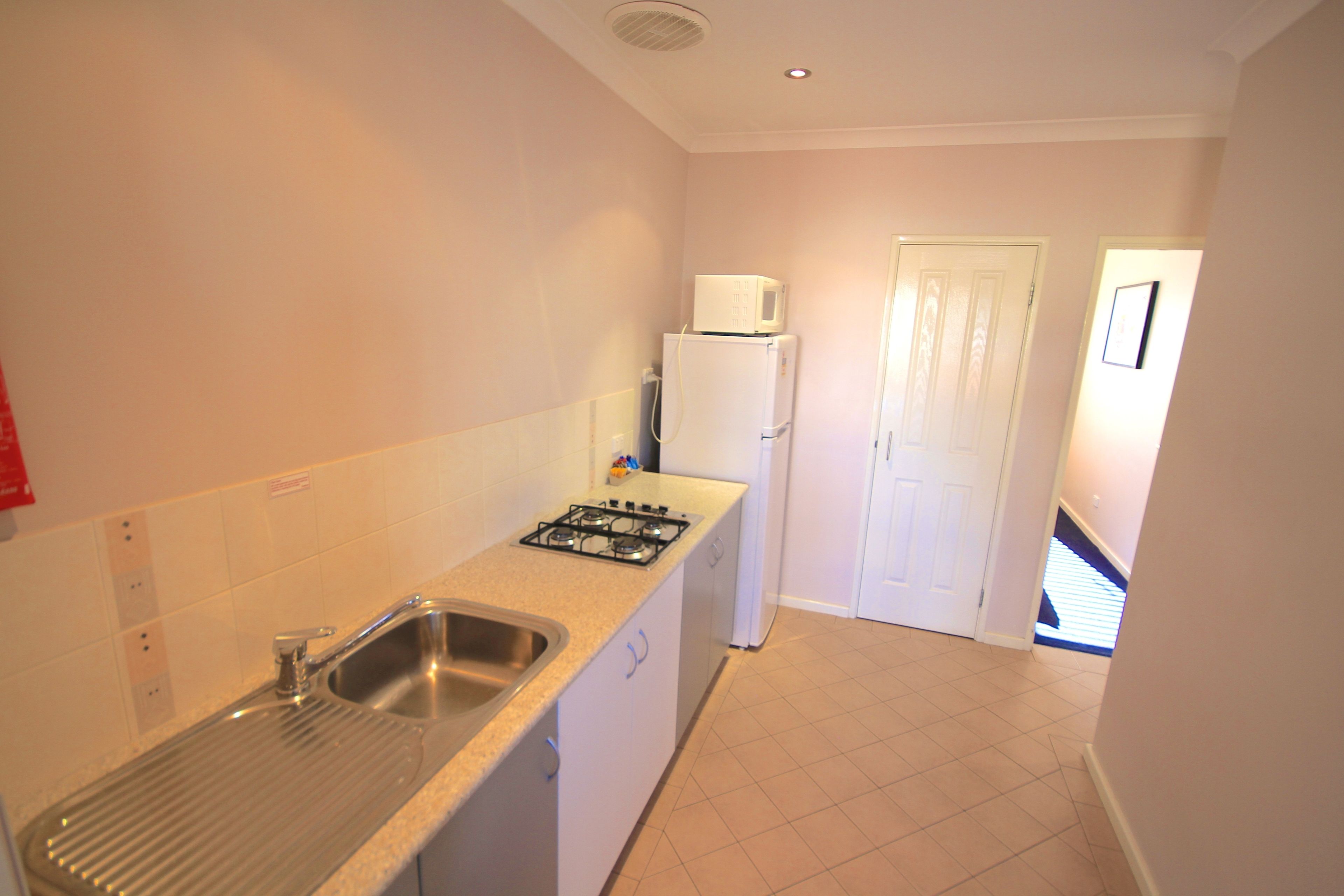 A compact kitchen with a sink, stove, and microwave.