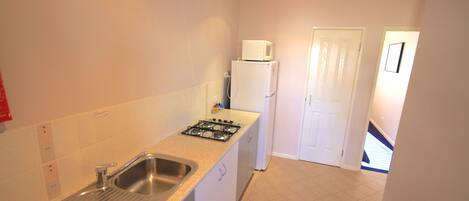 A compact kitchen with a sink, stove, and microwave.