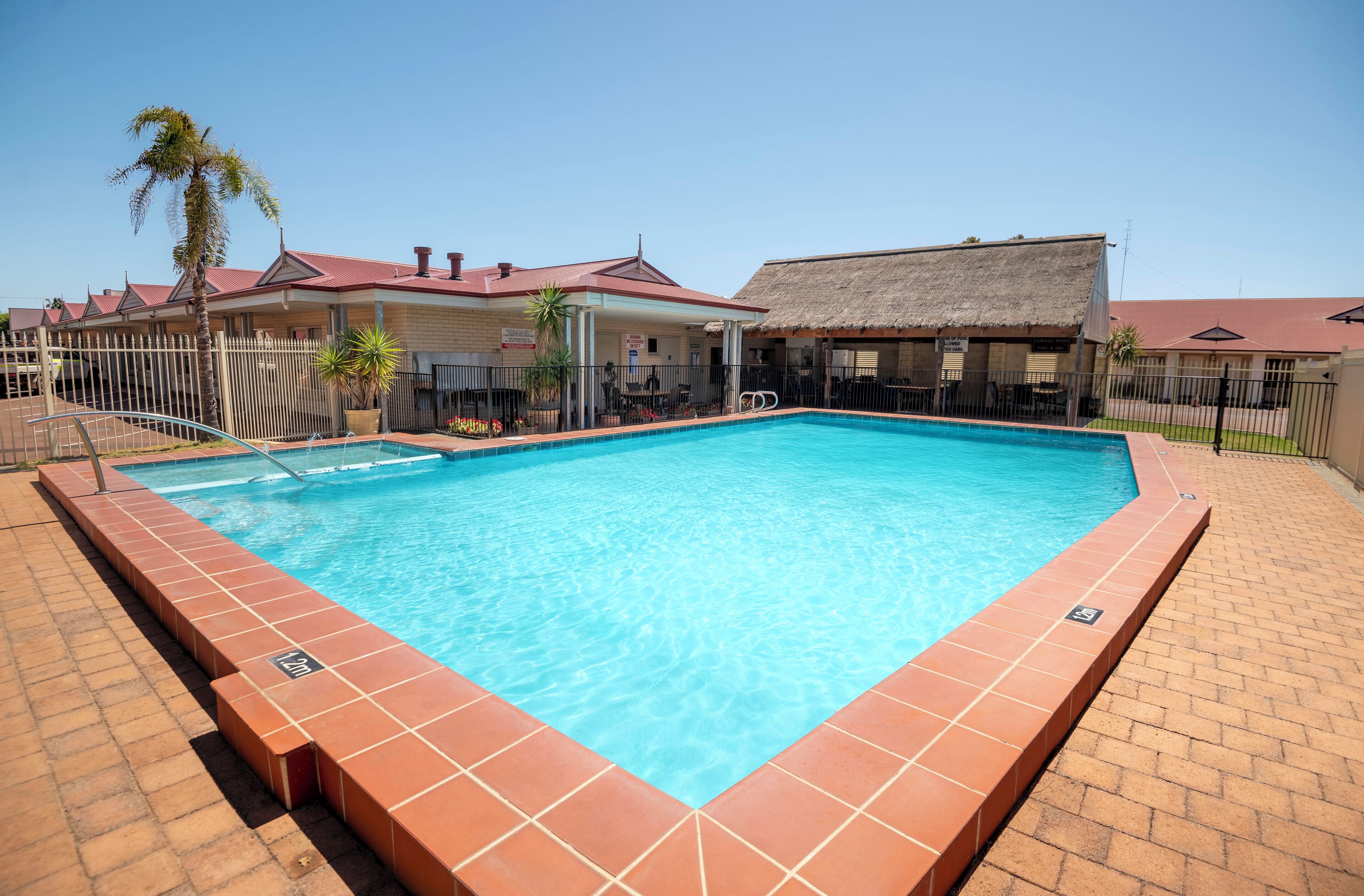 Una piscina rectangular con borde de azulejos, rodeada por un sendero de ladrillo.