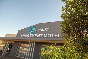 The exterior of the Bunbury Apartment Motel with a clear sign, a reception area, and a visible entrance.