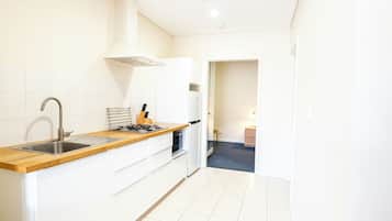 A modern kitchen with white cabinetry, a wooden countertop, a stainless steel sink, and a gas stove.