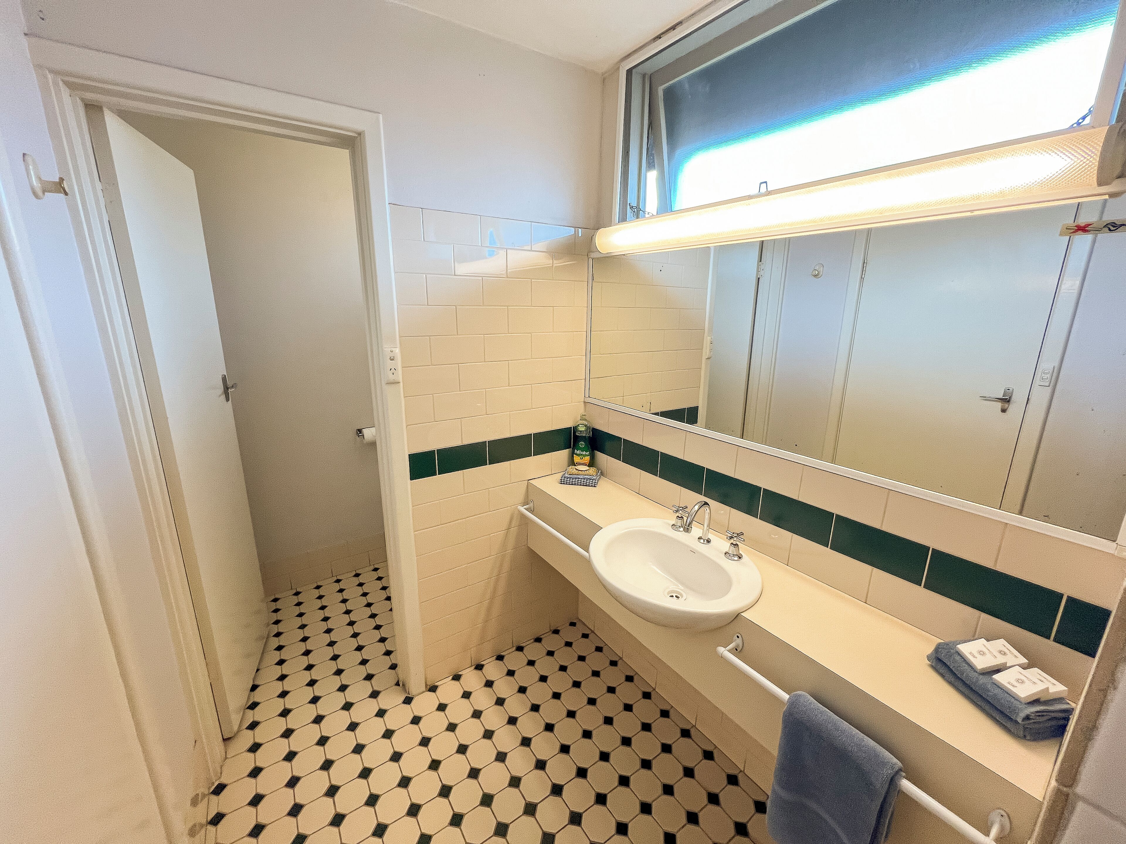 A bathroom with a white sink, a mirror, and a toilet.