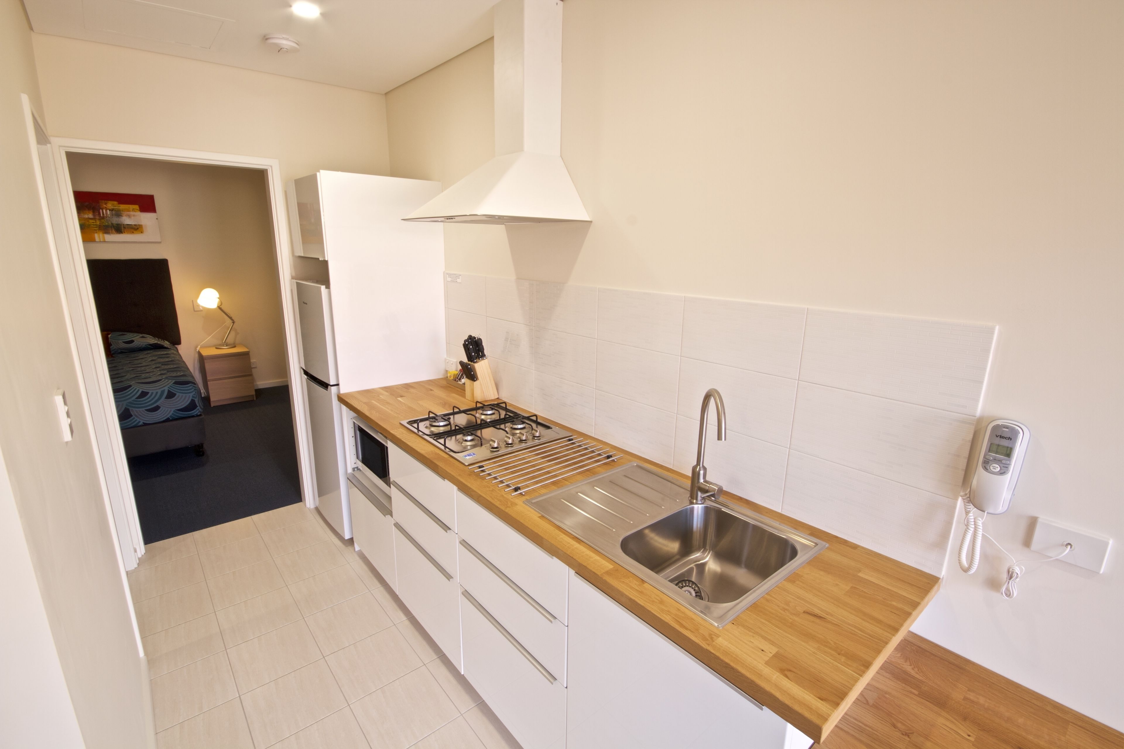 A compact kitchen with a wooden countertop, stainless steel sink, and a gas stove.