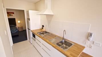 A compact kitchen with a wooden countertop, stainless steel sink, and a gas stove.