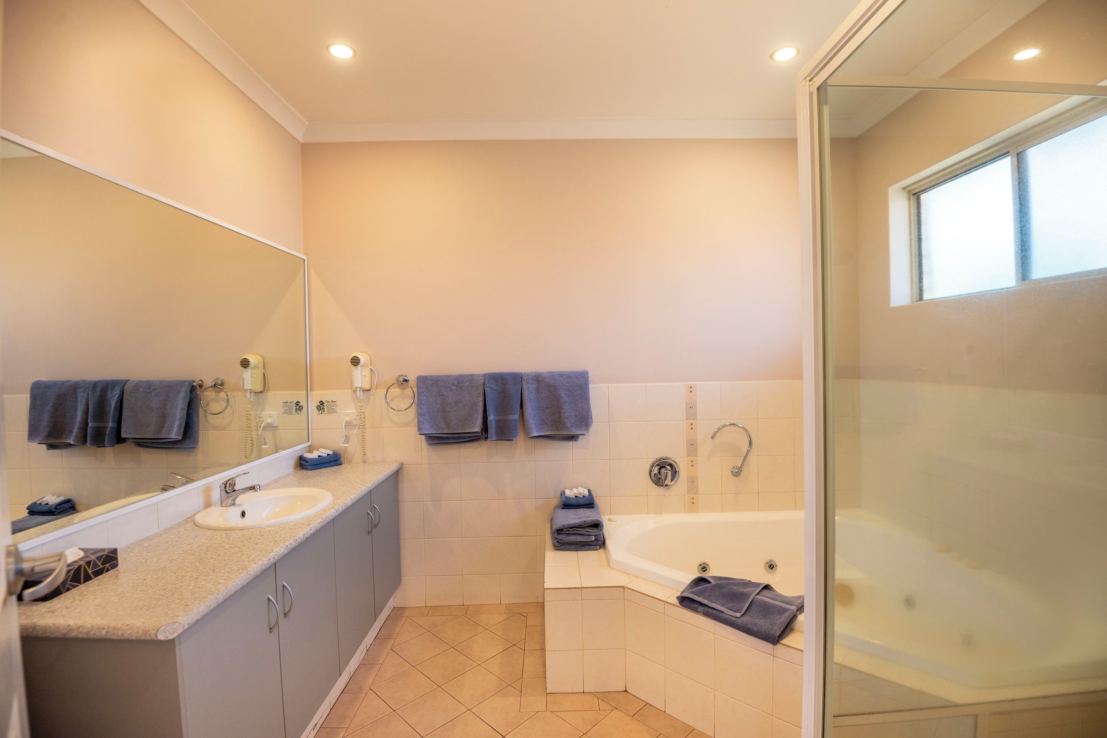 Un baño moderno con lavamanos doble, bañera y cabina de ducha con mampara de vidrio.