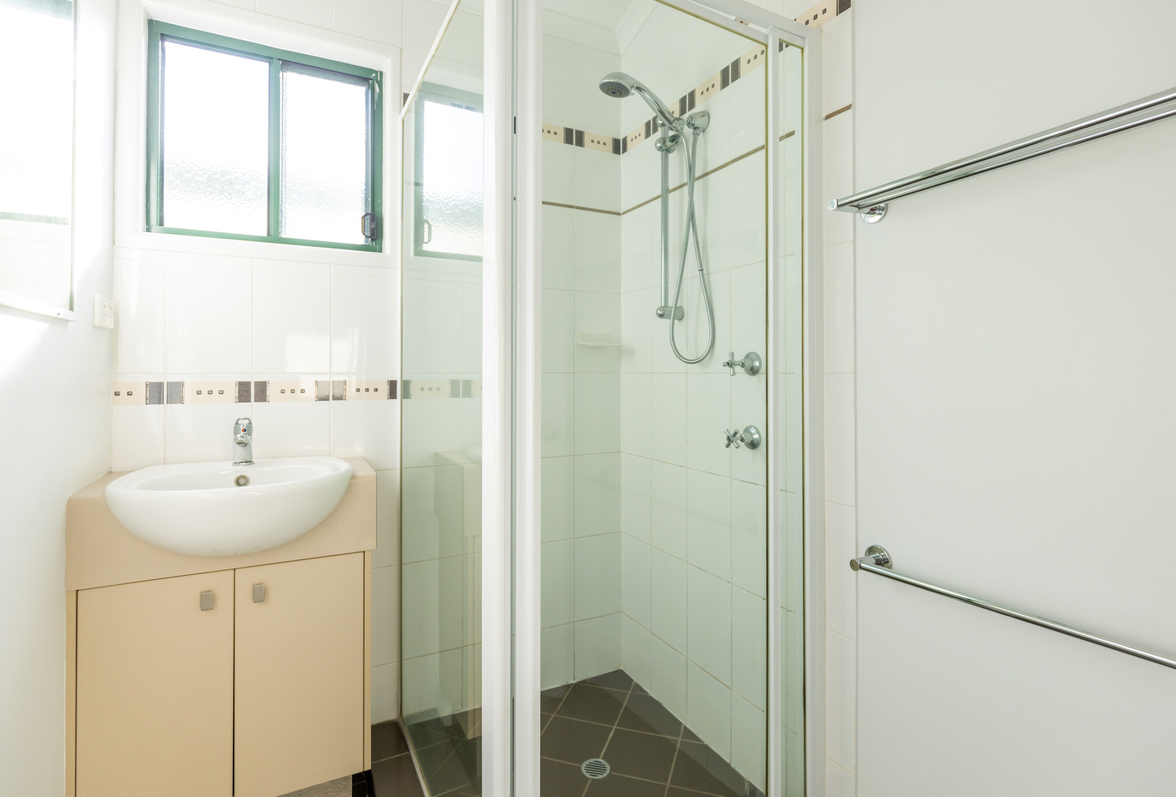 A bathroom with a sink, glass shower enclosure, and a towel rack.