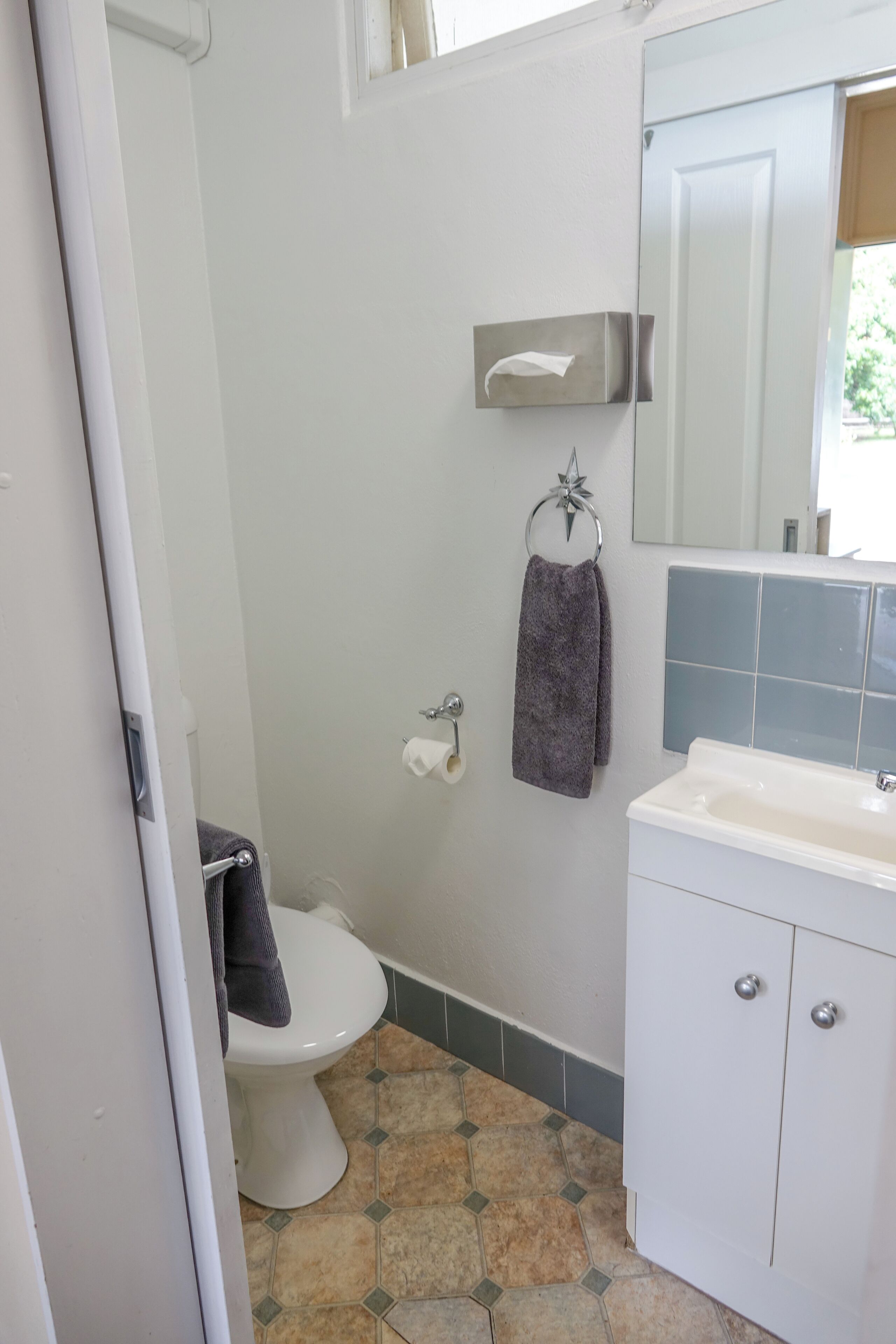 Un baño con inodoro, lavamanos y espejo.
