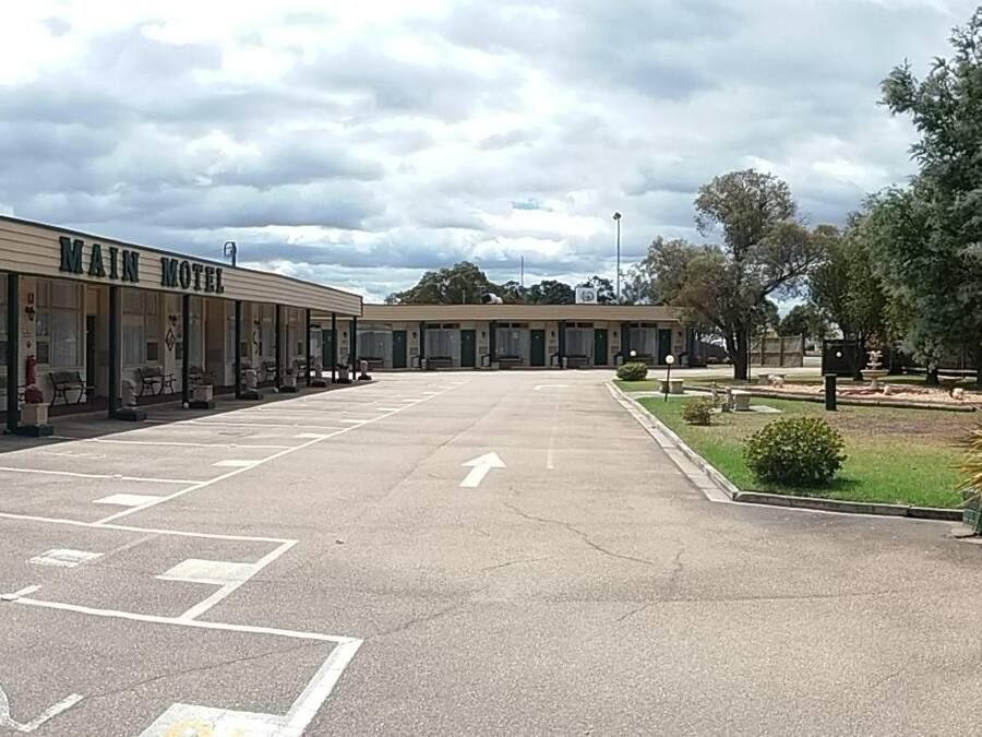 A motel with a parking lot, outdoor seating, and a small garden area.