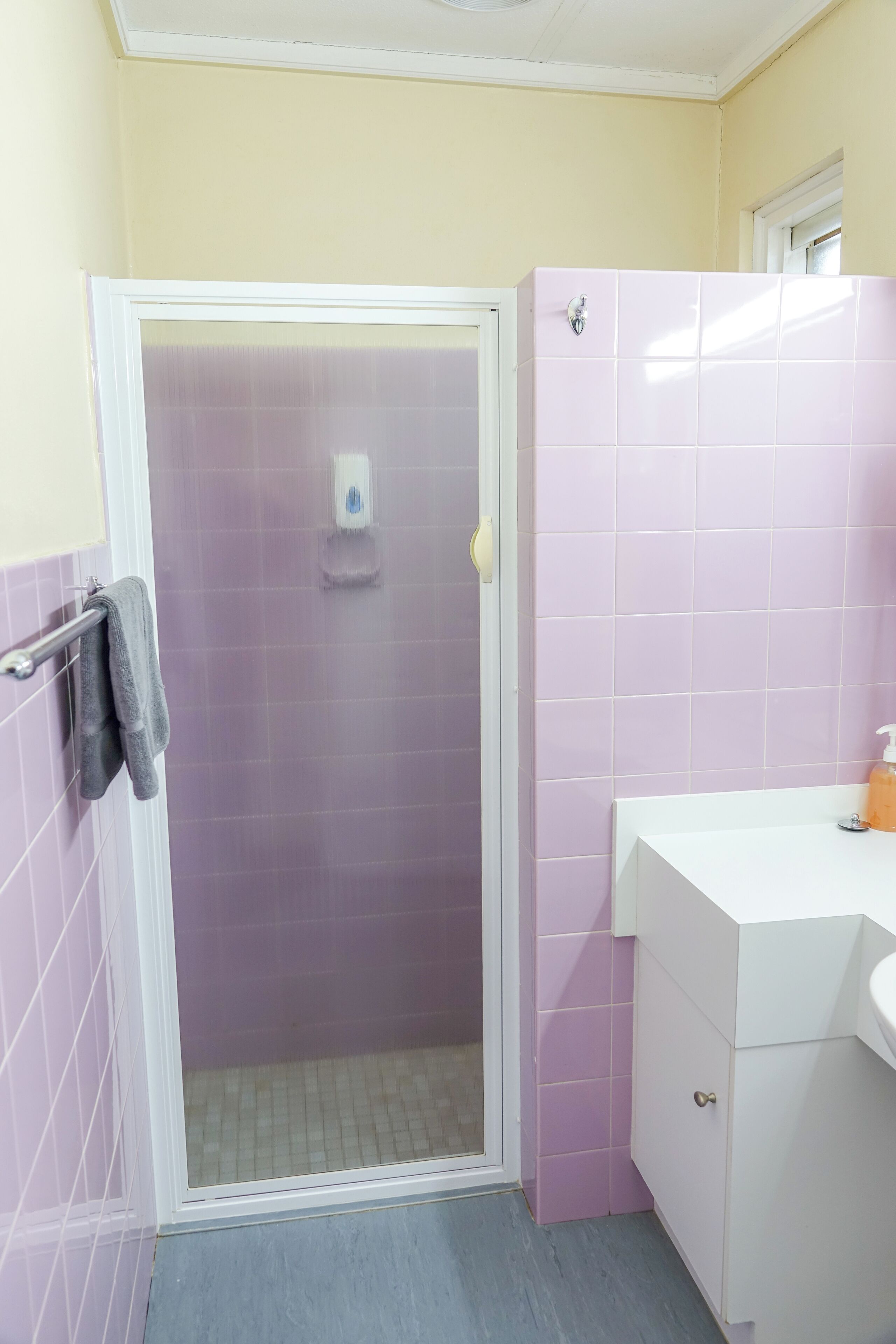 A bathroom with a shower, a sink, and a towel rack.