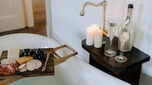 A bathroom with a bathtub, a wooden tray with snacks, candles, and bottles. - The Abbey (Warwick)