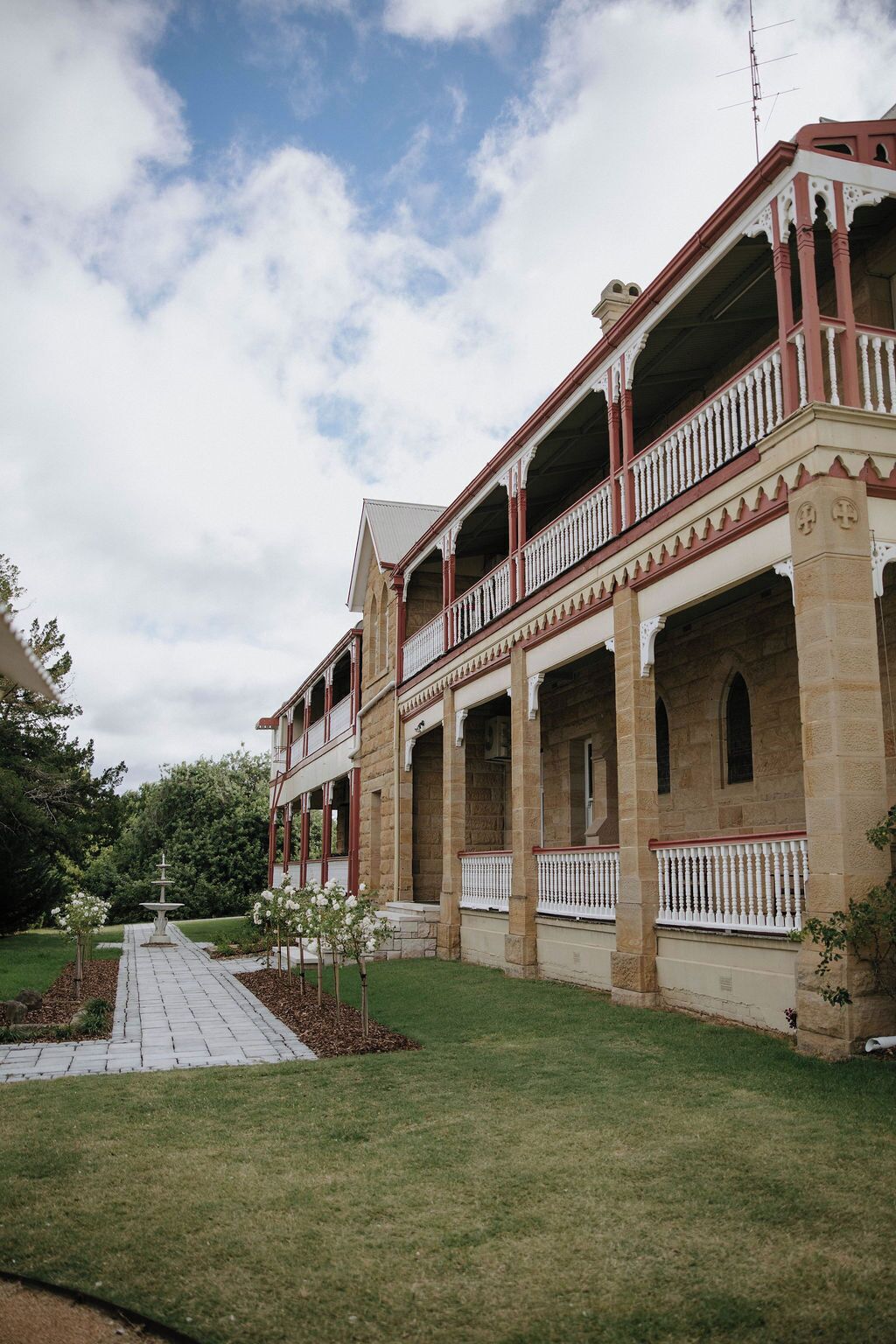 A large, two-story building with a symmetrical facade, multiple balconies, and a central fountain.