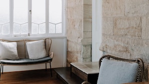 A room with stone walls, a wooden floor, a bench, a chair, and a table. - The Abbey (Warwick)