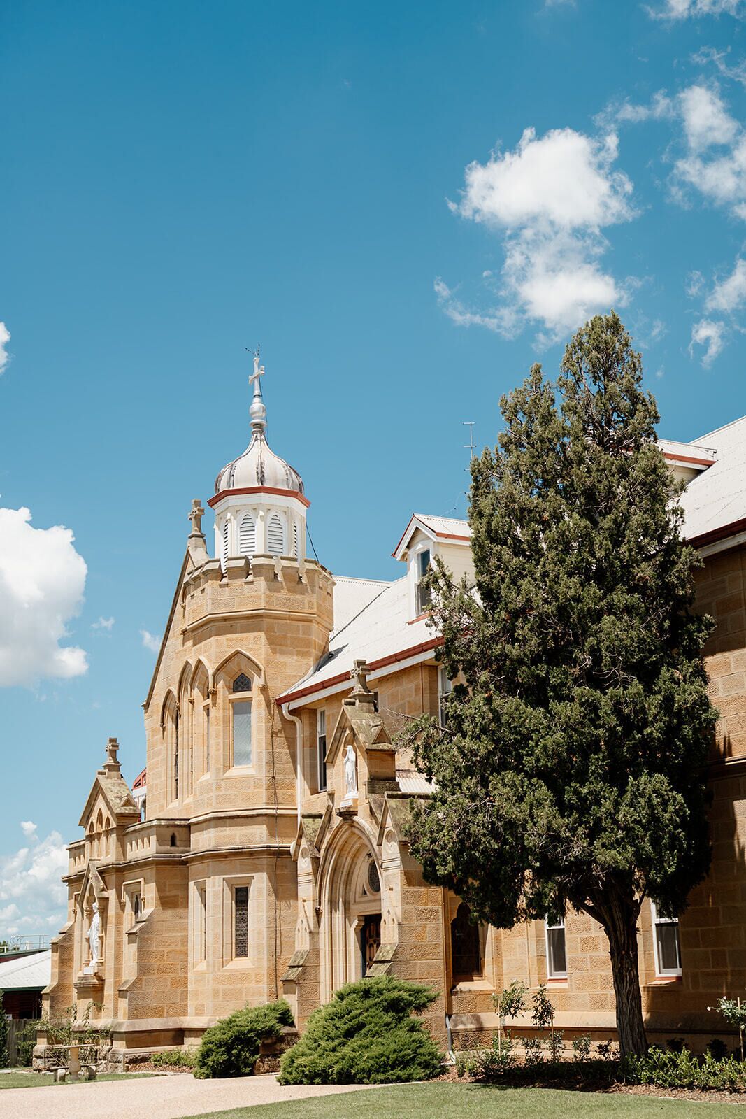 A historic building with a prominent dome and arched windows, surrounded by well-maintained greenery.