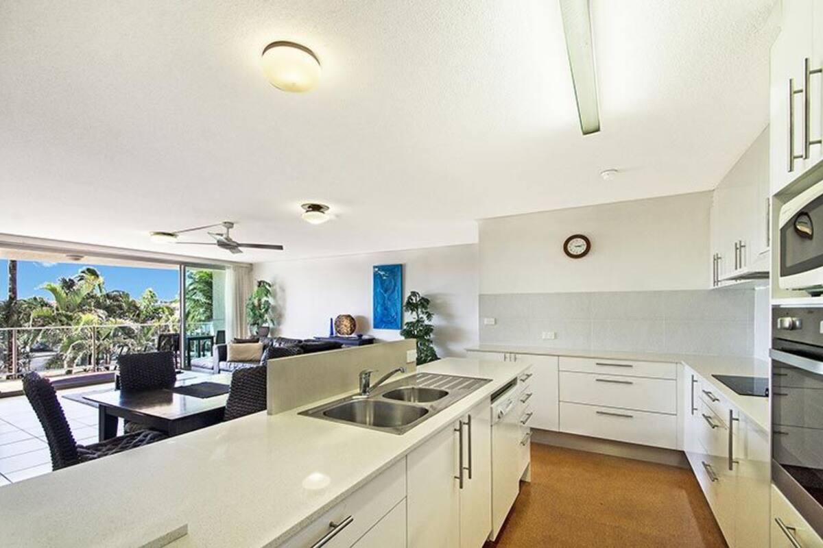 Een moderne keuken met witte kastjes, een dubbele spoelbak en een groot eiland.