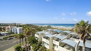 Een kusthotel met meerdere gebouwen, een parkeerplaats en uitzicht op het strand.