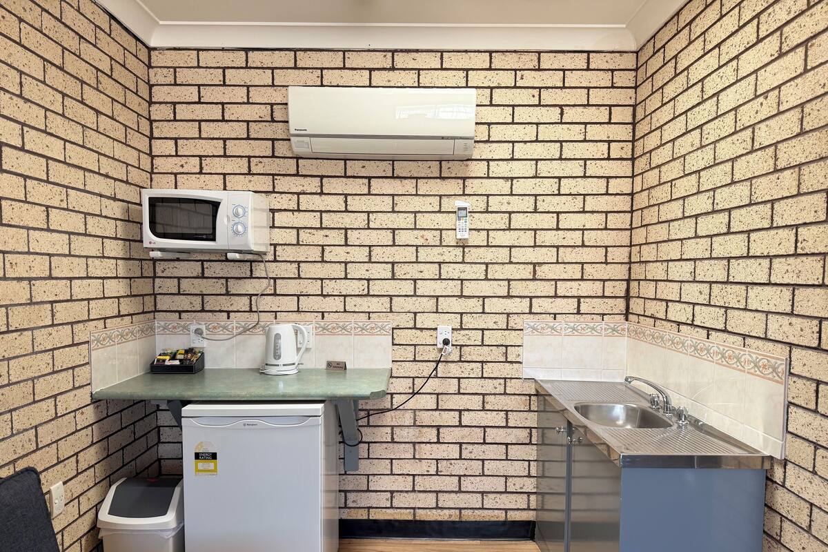 A compact kitchenette with a microwave, kettle, and small refrigerator.