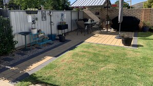 A patio with a brick barbecue, outdoor seating, and potted plants. - Cowra Crest Motel (Cowra)