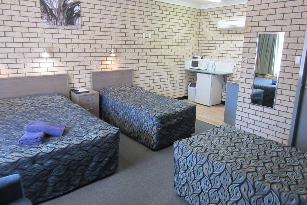 A hotel room with two beds, a small kitchenette, and a mirror.