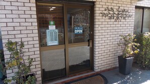 A storefront with a brick facade, a glass door, and a sign indicating business hours. - Cowra Crest Motel (Cowra)