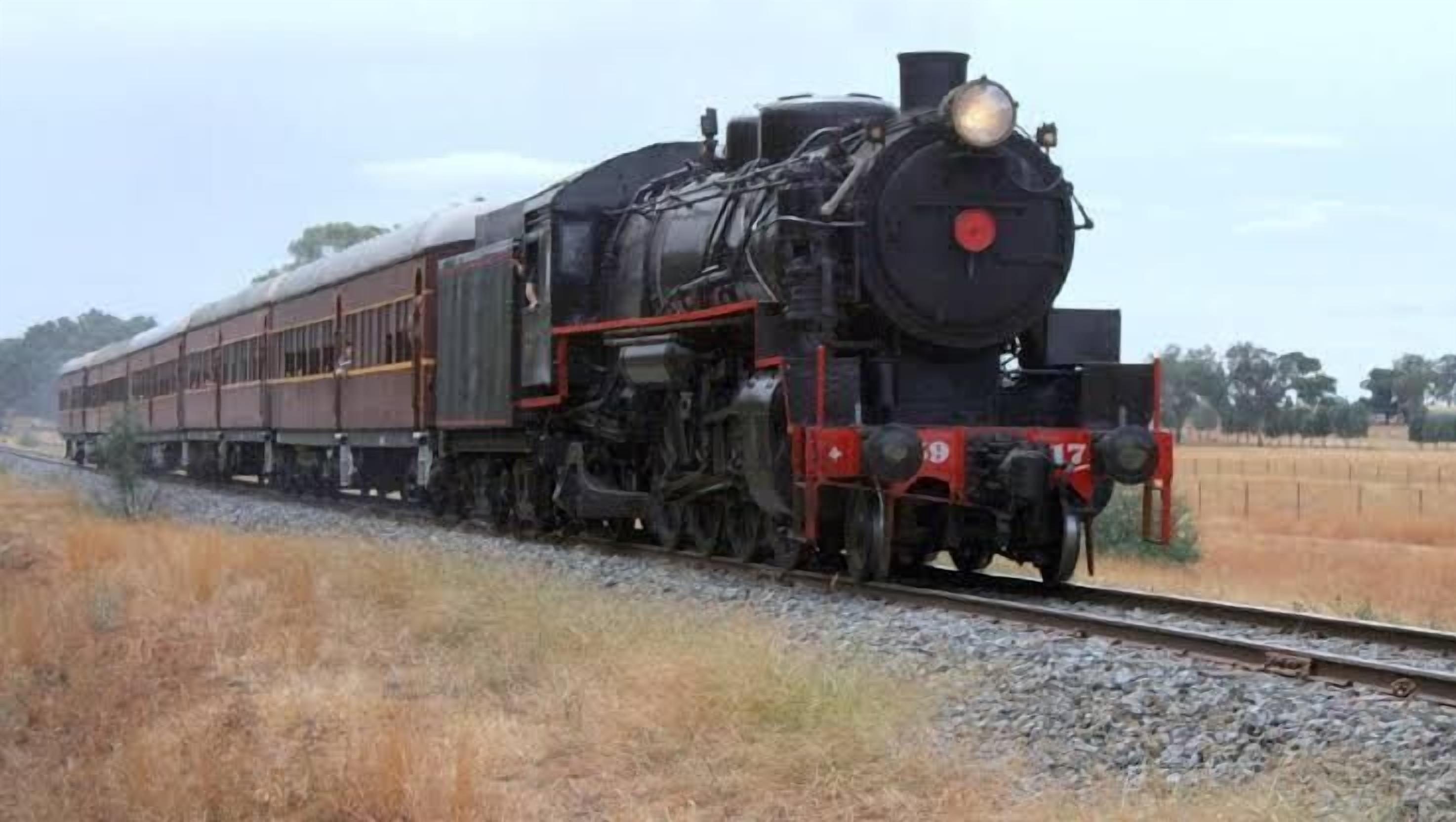 A steam locomotive pulling a freight train on a single-track railway.