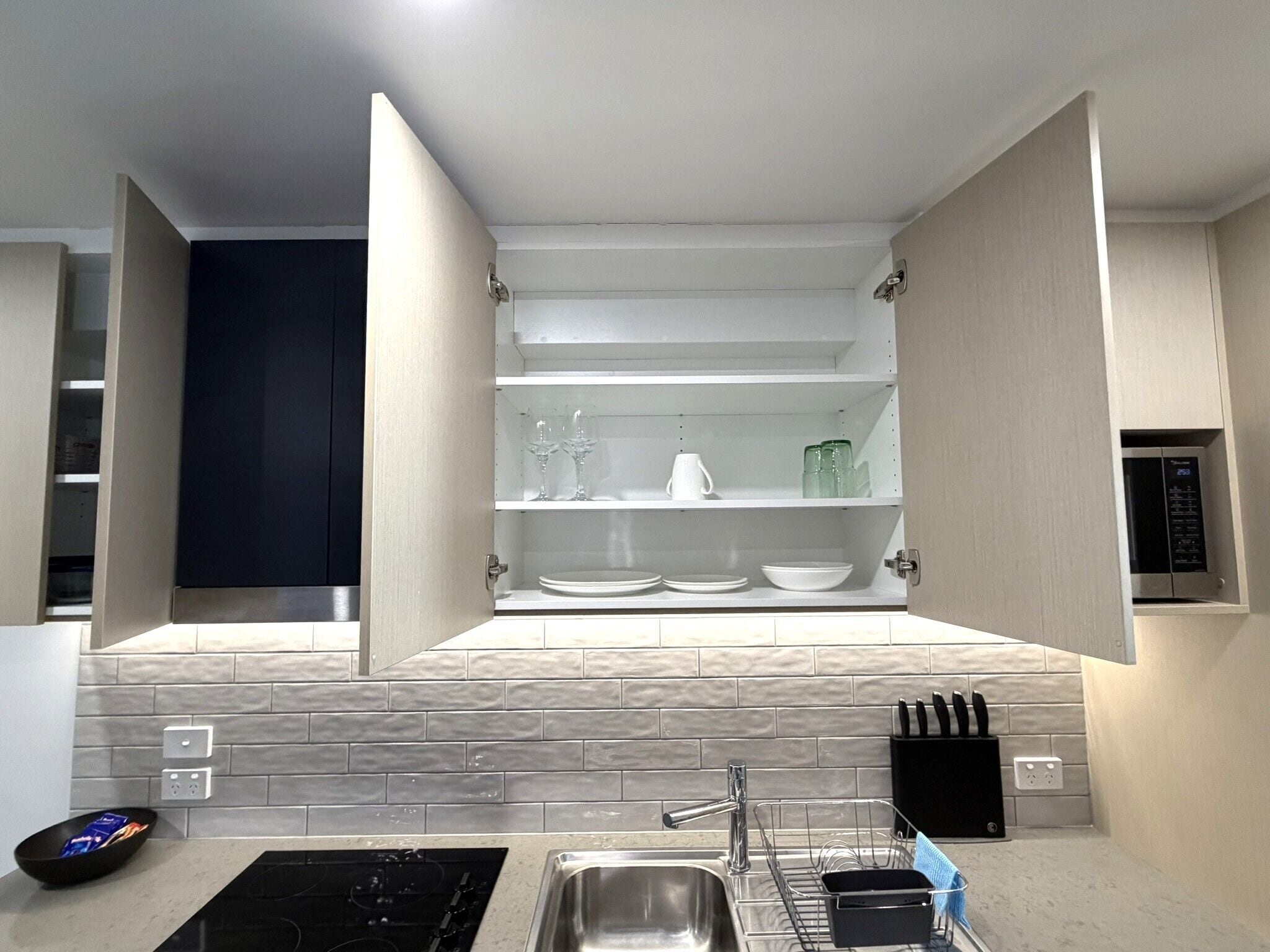 A kitchen with open cabinets, a sink, and a stove.