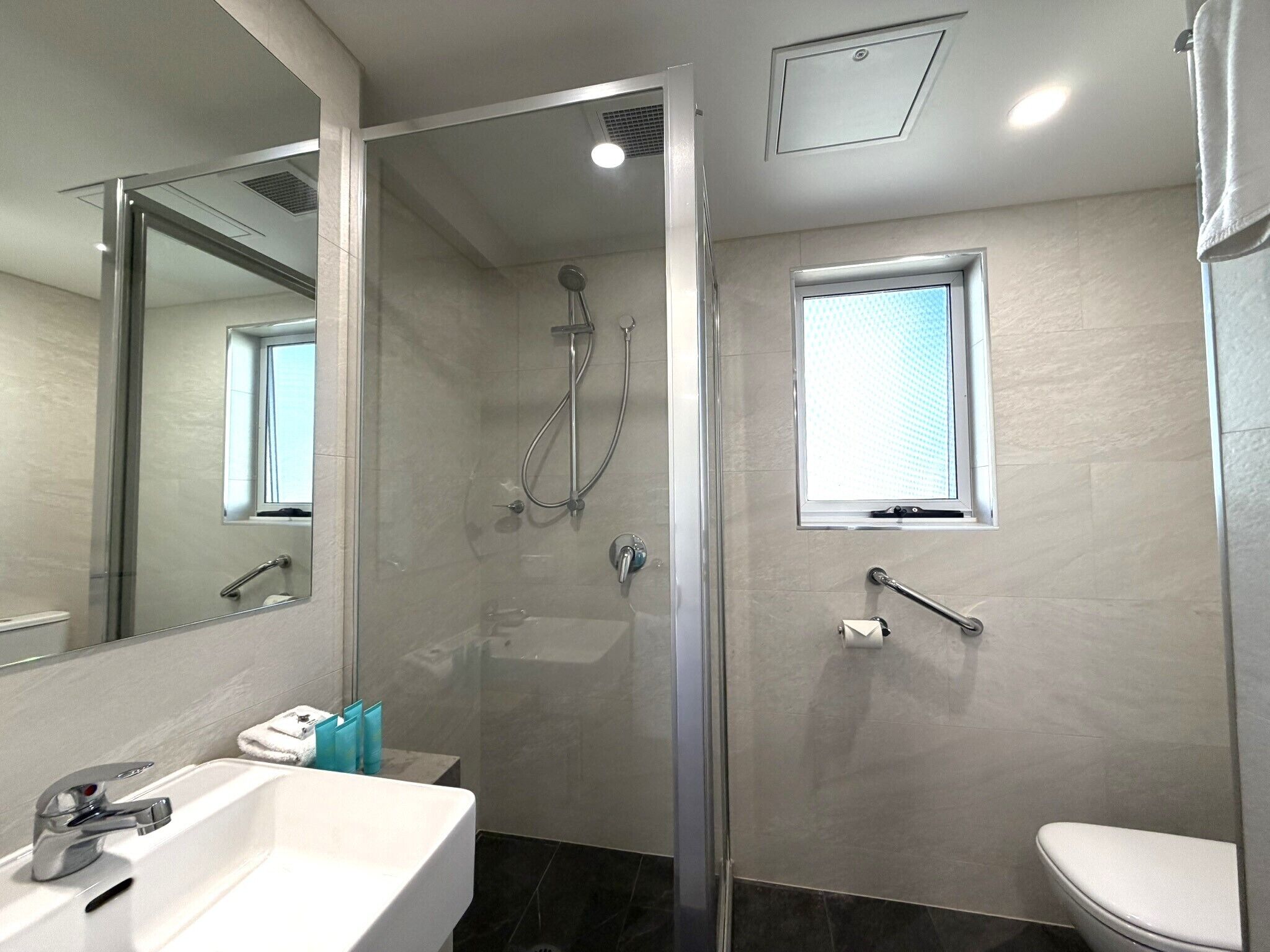 A modern bathroom with a glass-enclosed shower, a white sink, and a toilet.