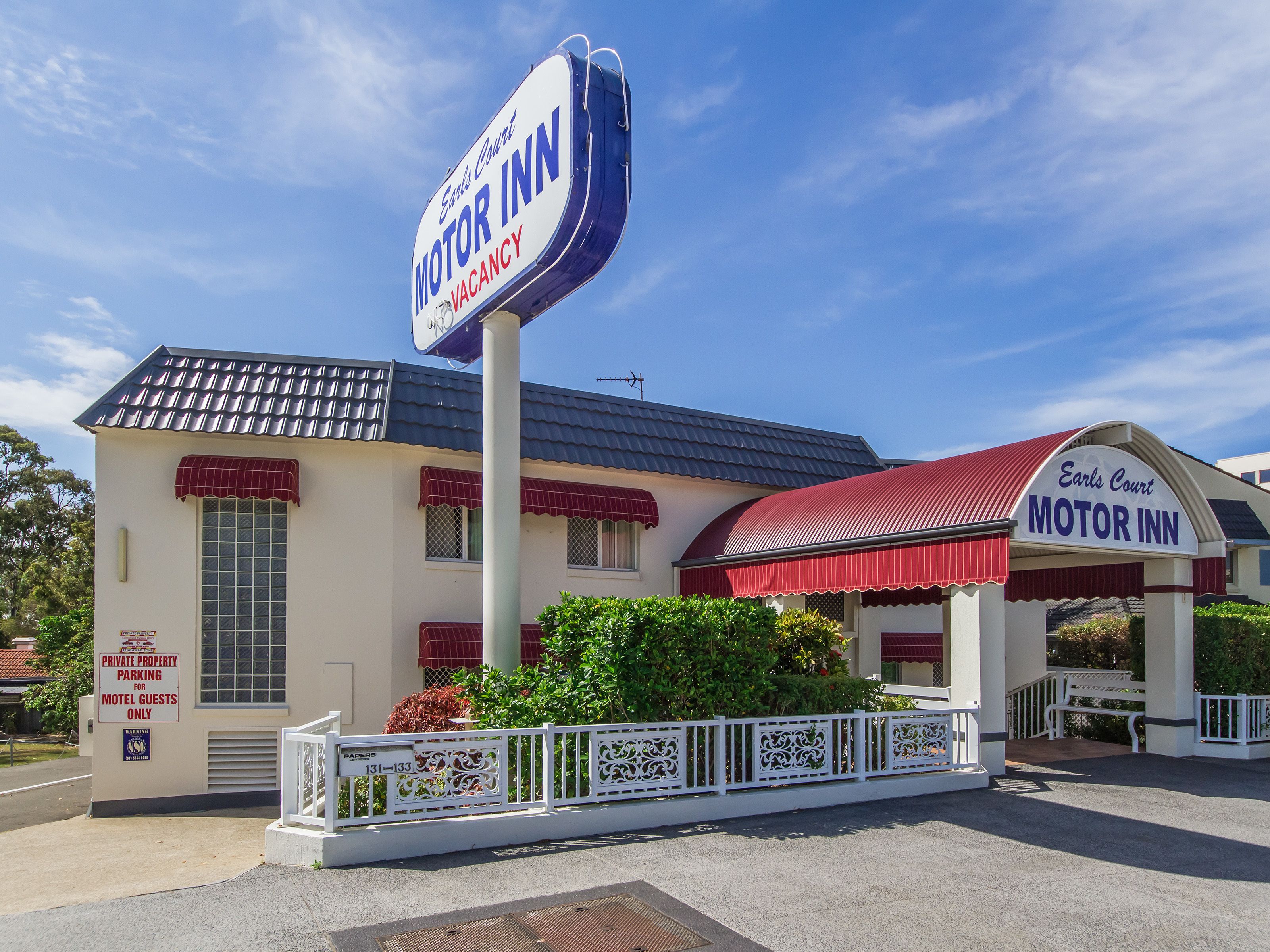 A motel with a large sign reading "Earl's Court Motor Inn" and a sign indicating "Private Property Parking for Motel Guests Only."
