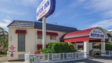 A motel with a large sign reading "Earl's Court Motor Inn" and a sign indicating "Private Property Parking for Motel Guests Only."