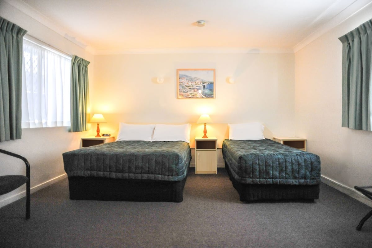 A hotel room with two beds, a painting on the wall, and two bedside lamps.