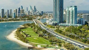 A coastal cityscape with high-rise buildings, a marina with boats, and a road running parallel to the coast. - Southport Motel & Apartments (Southport)