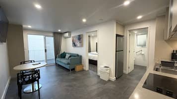Un apartamento moderno con comedor, kitchenette, sala de estar y un balcón.