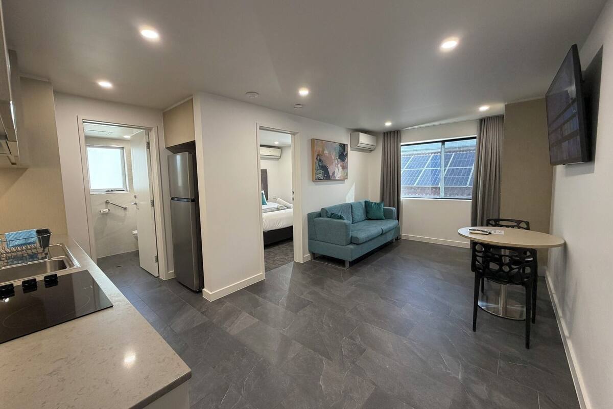 A modern apartment with a kitchen, a dining area, a living room, and a bedroom.