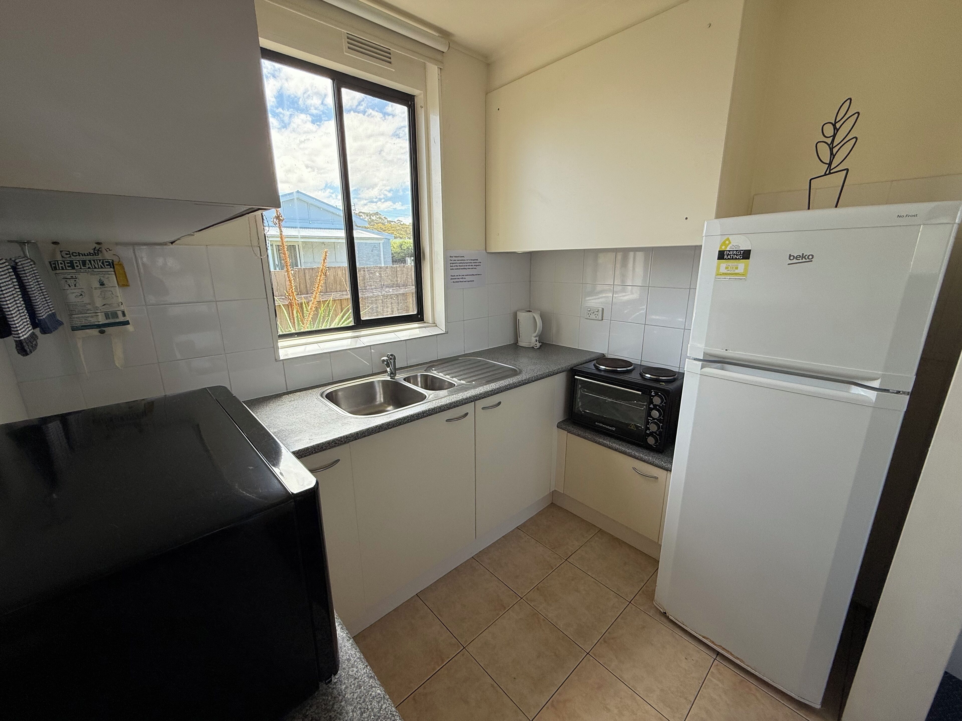 A compact kitchen with a sink, a stove, a microwave, and a refrigerator.