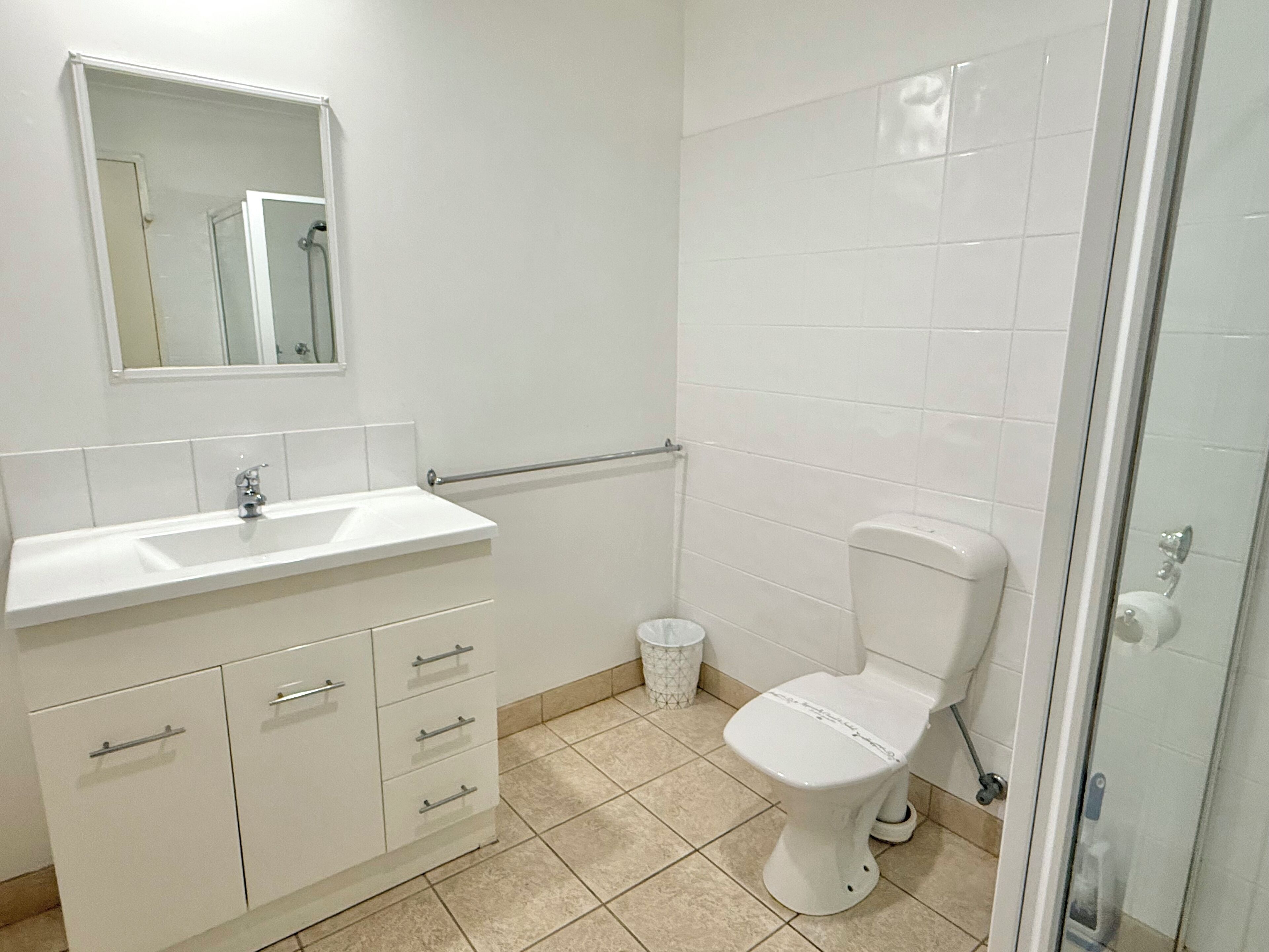 Une salle de bain avec un lavabo blanc, un miroir et des toilettes.