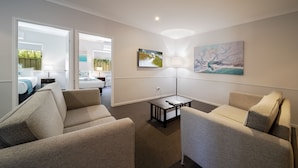 A modern hotel room with a sofa, a small table, and a painting on the wall.