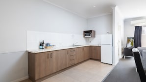 A modern kitchen with wooden cabinets, a microwave, and a refrigerator.