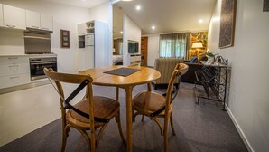 A compact living space with a dining area, kitchenette, and a living room with a sofa and lamp. - Bright Mystic Valley (Bright)