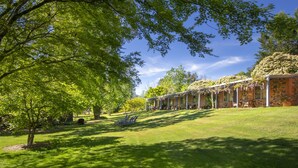 A stone building with a covered patio area, surrounded by lush green trees and a well-maintained lawn. - Bright Mystic Valley (Bright)