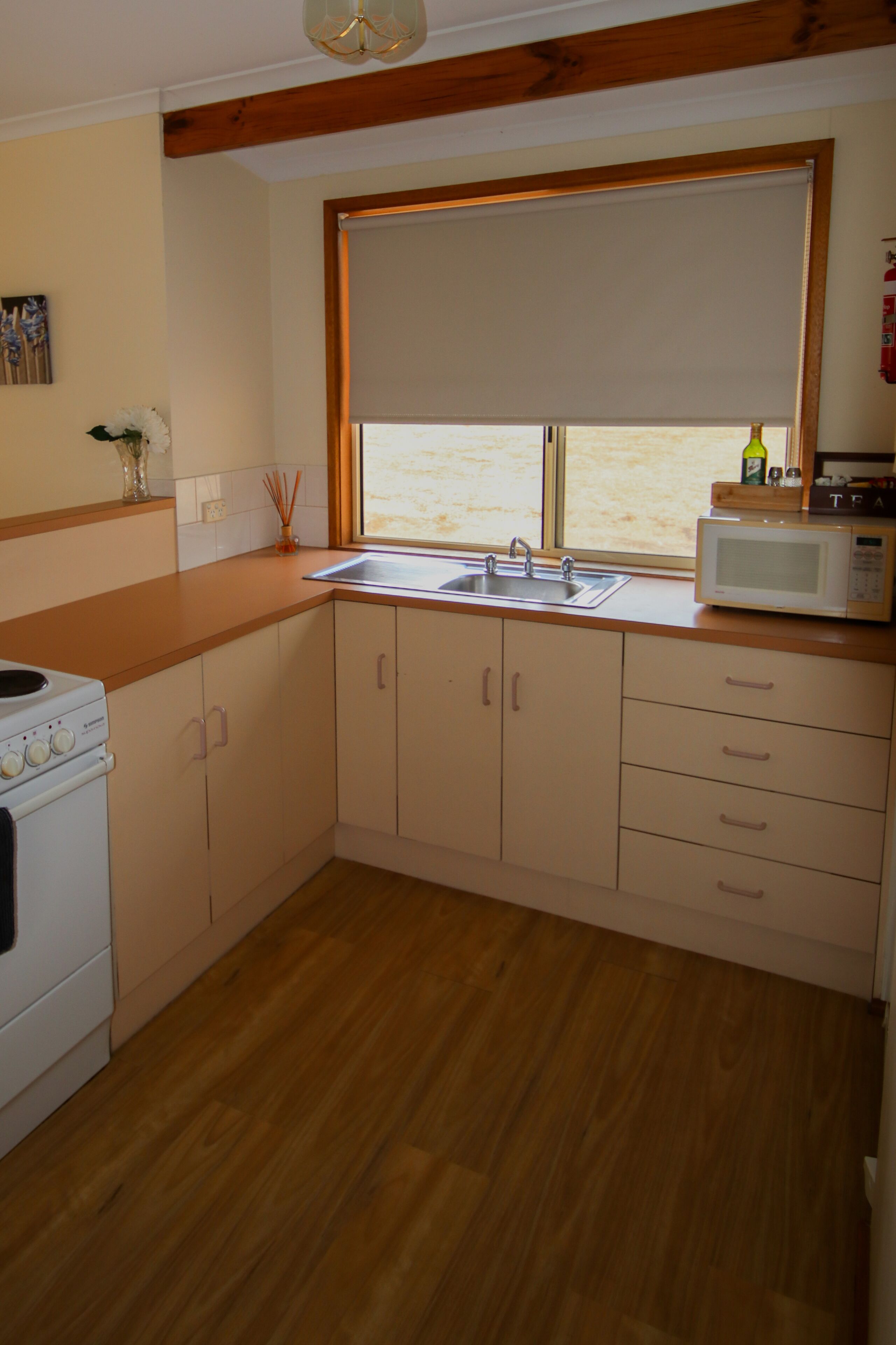 A kitchen with wooden cabinets, a sink, a microwave, and a window with a view.