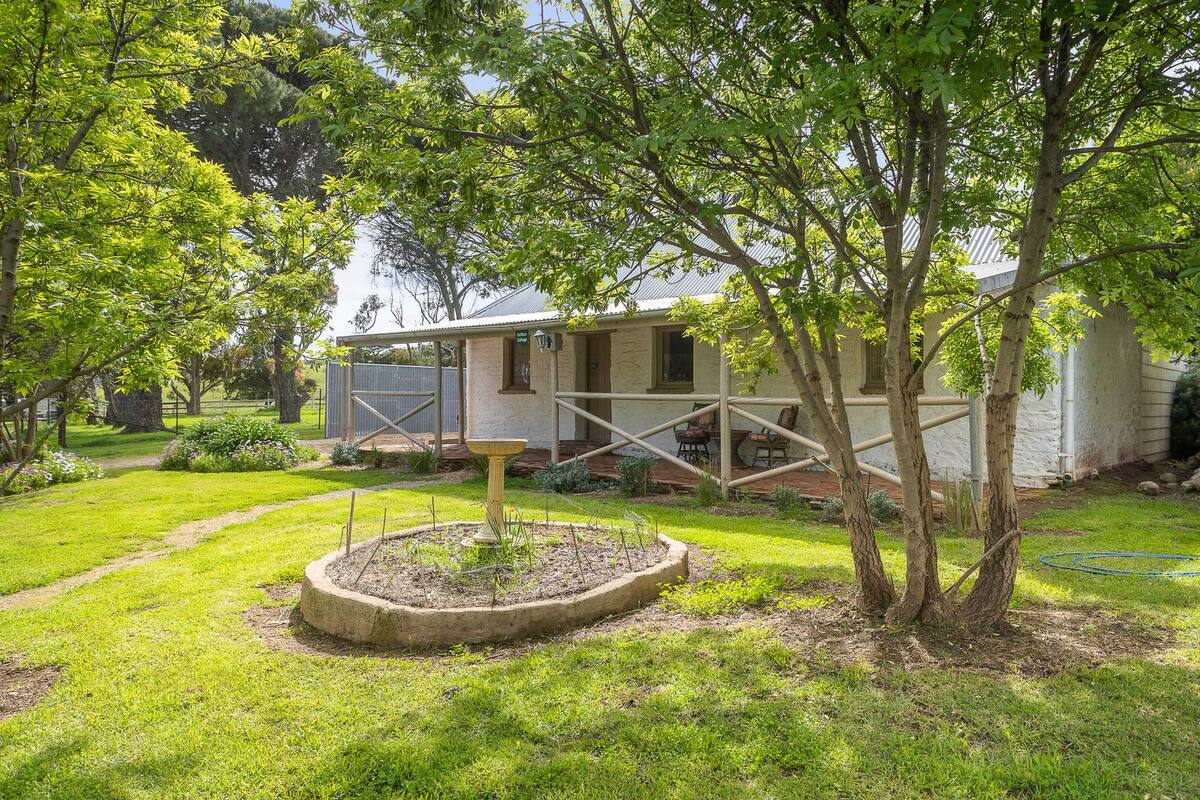 Une maison avec un jardin, une petite terrasse et une clôture en bois.
