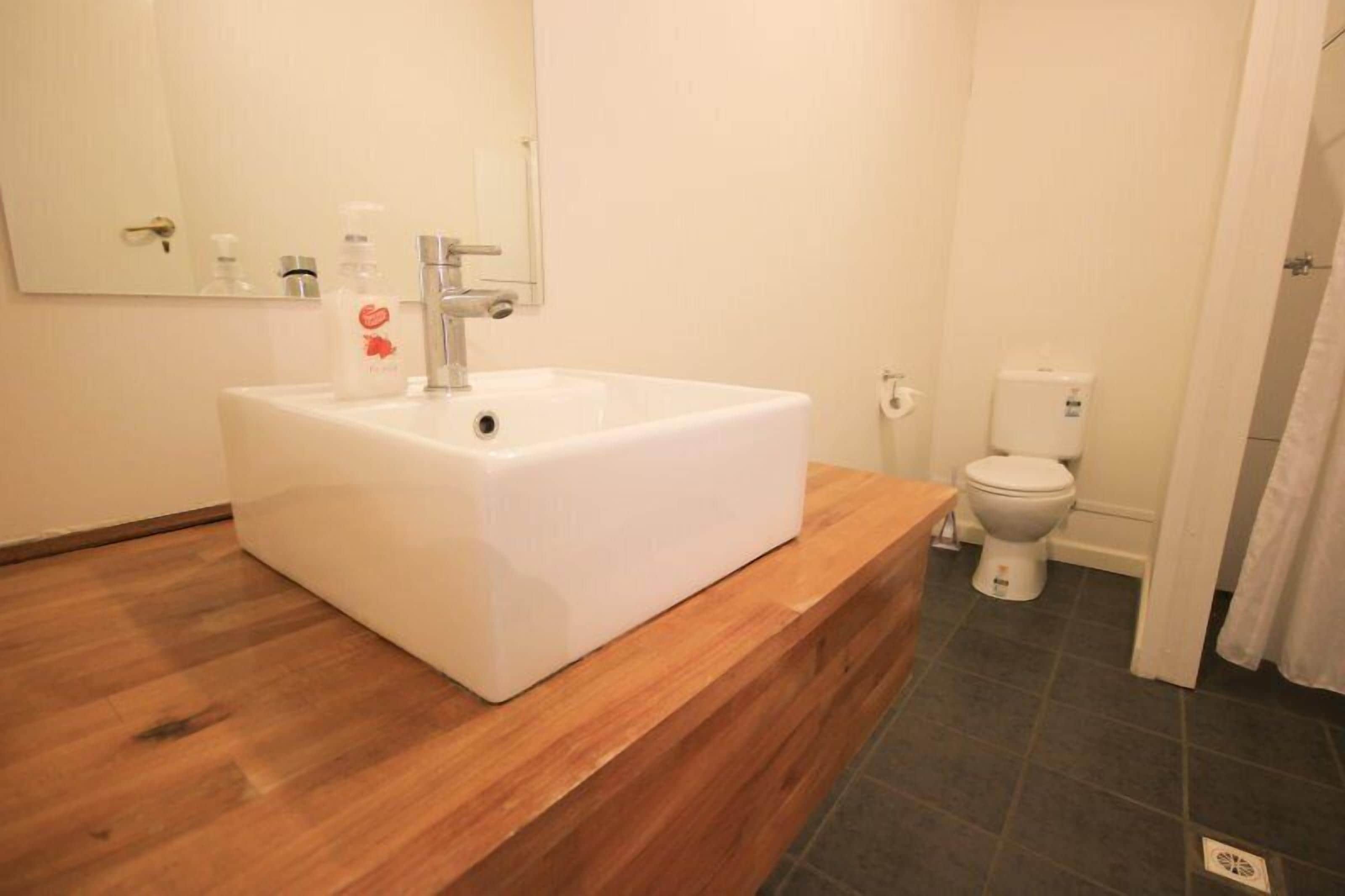 Un baño con lavamanos blanco, encimera de madera y un inodoro.