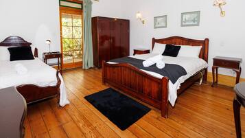 Een hotelkamer met twee houten bedden, een kledingkast, een klein tafeltje en een zwart vloerkleed.